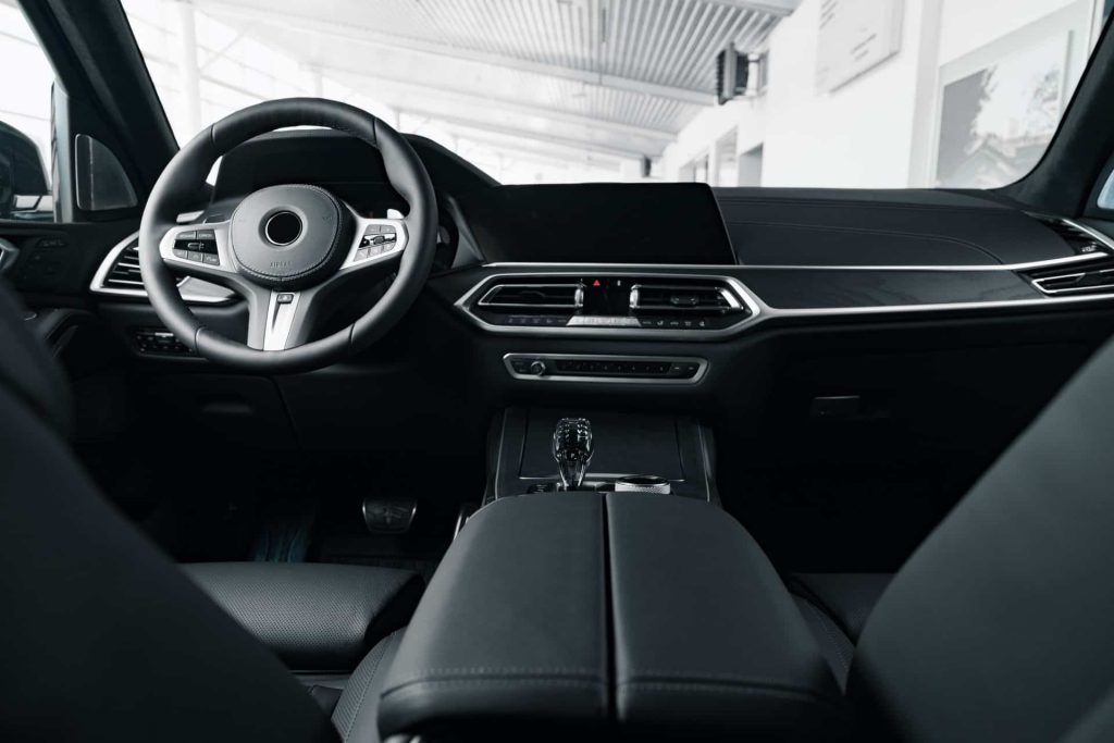 Interior view of a modern car with an elegant dashboard and digital display reminiscent of IAA innovations, central control panel and steering wheel. The design features black and metallic accents, conveying a sophisticated, minimalist aesthetic.