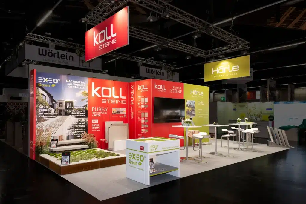 Messestand der KOLL GmbH auf der GaLaBau in Nürnberg mit rotem Logoblender, grüner Härle-Wand und begrüntem Musterfeld im Vordergrund.