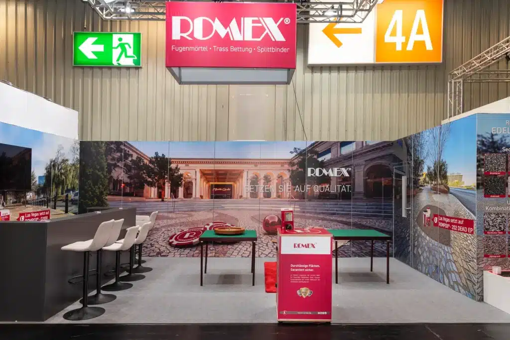 Messestand von Romex auf der GaLaBau in Nürnberg mit rotem Deckenblender, Bildwand Setzen Sie auf Qualität und Spieltischen.