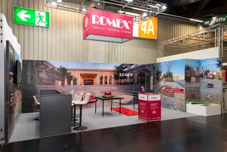 Romex-Stand auf der GaLaBau in Nürnberg aus dem Gang gesehen, mit rotem Logoblender, Bildwand und Produktmustern an der Seitenwand.