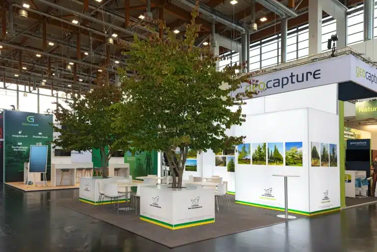 Messebau für VF-Pflanzen von Falkenhayn auf der GaLaBau Nürnberg mit Baum in der Standmitte, weißen Theken und geocapture-Blende.